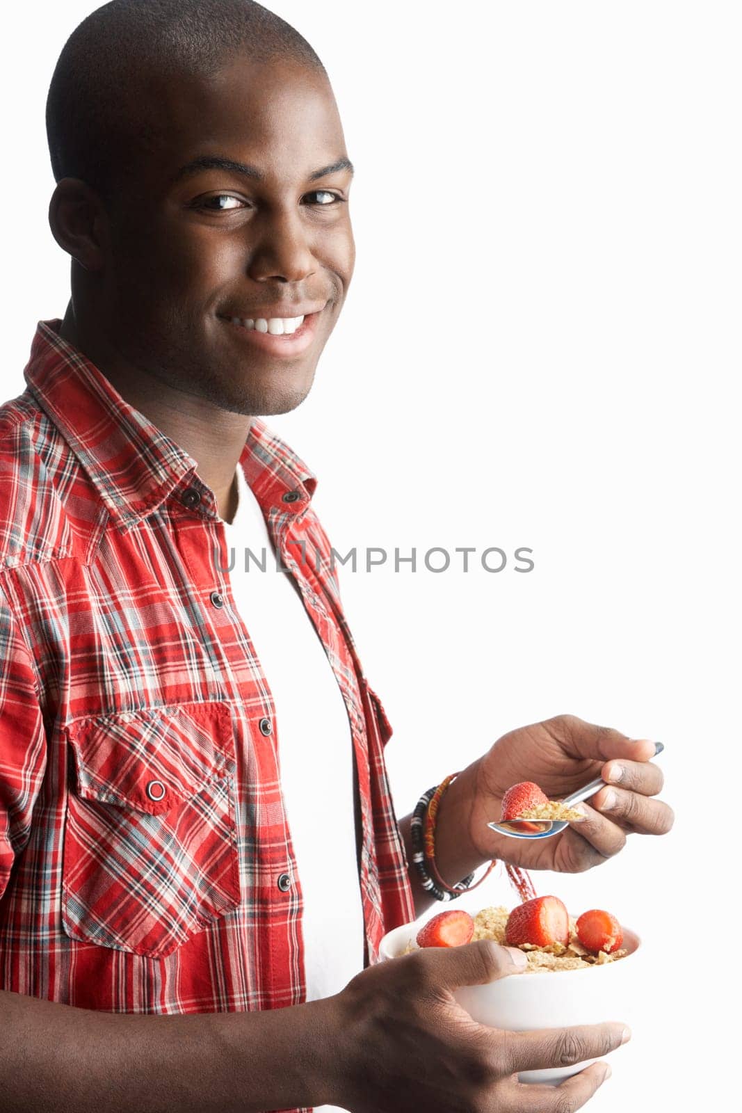 Young Man Eating Bowl Of Healthy Breakfast Cereal In Studio