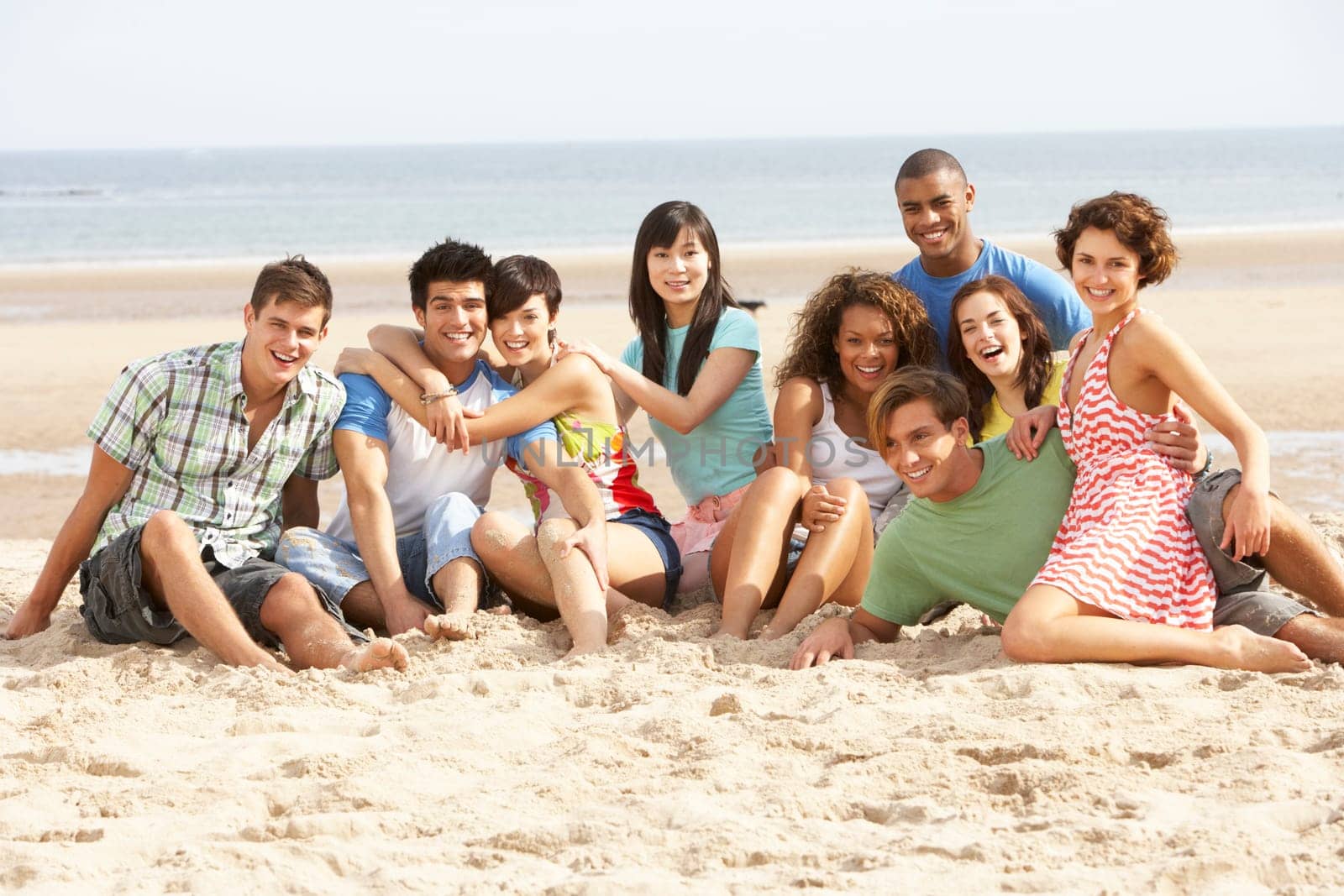 Group Of Friends Sitting On Beach Together