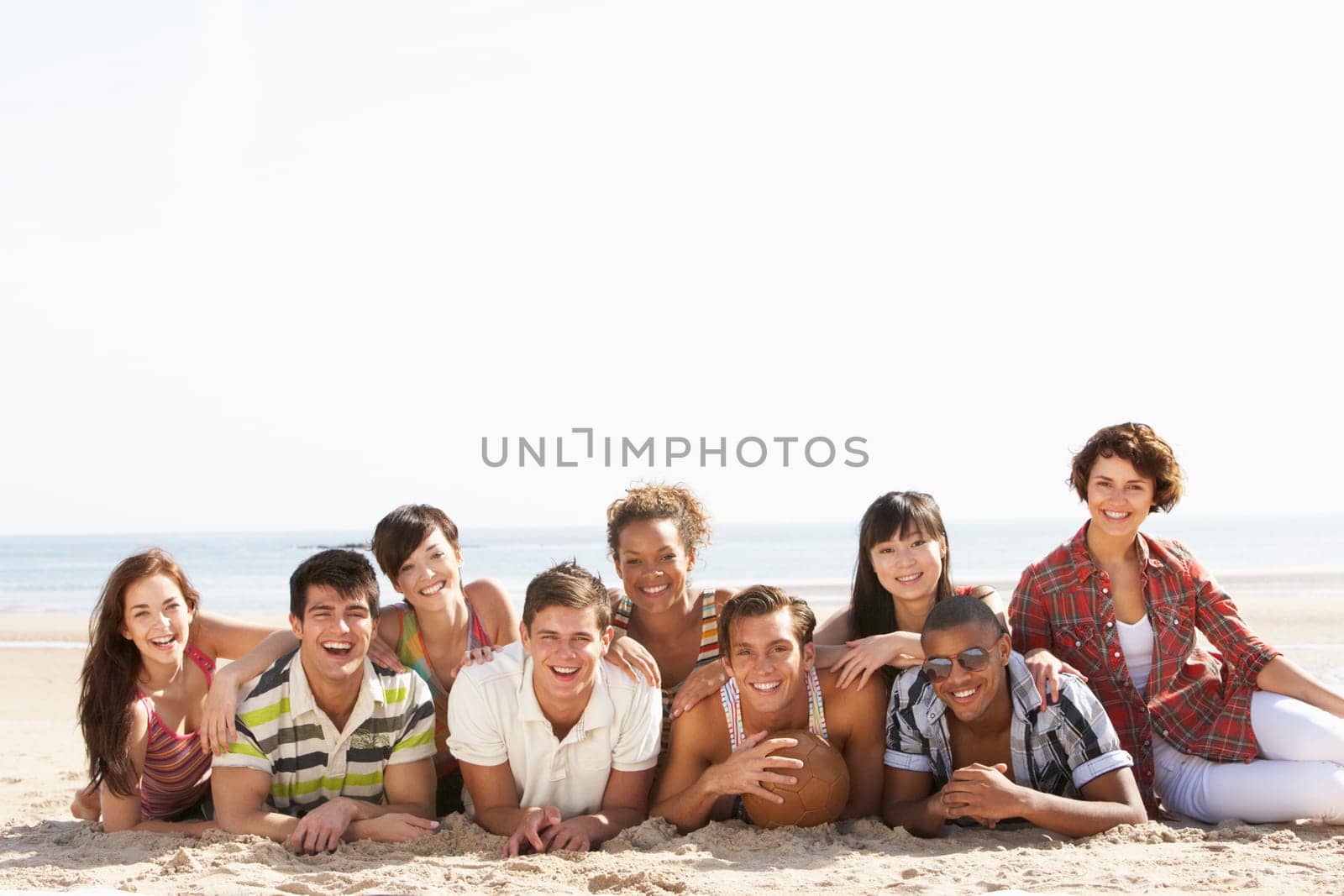 Group Of Friends Sitting On Beach Together