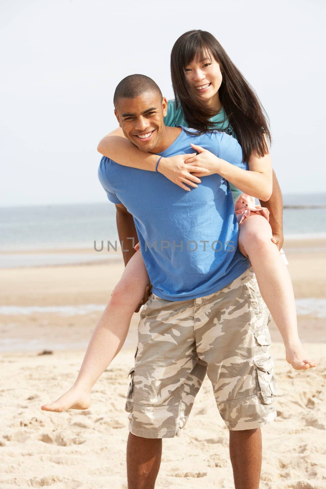Young Couple Having Piggyback Fun On Beach