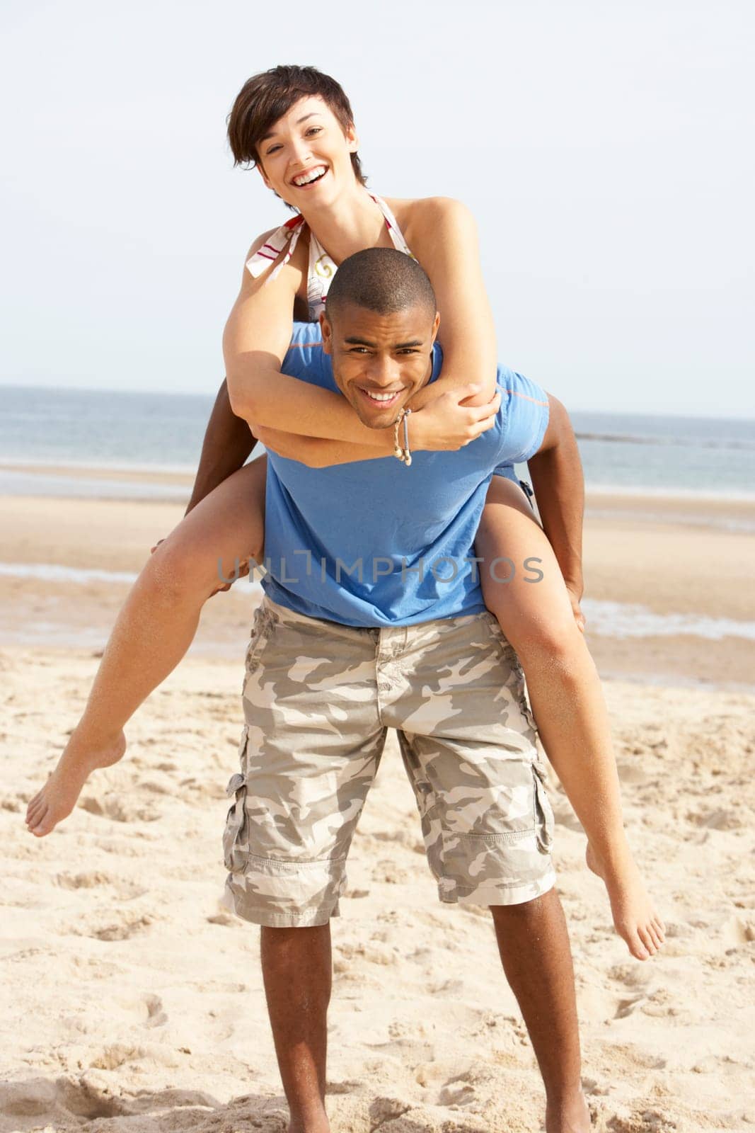 Young Couple Having Piggyback Fun On Beach