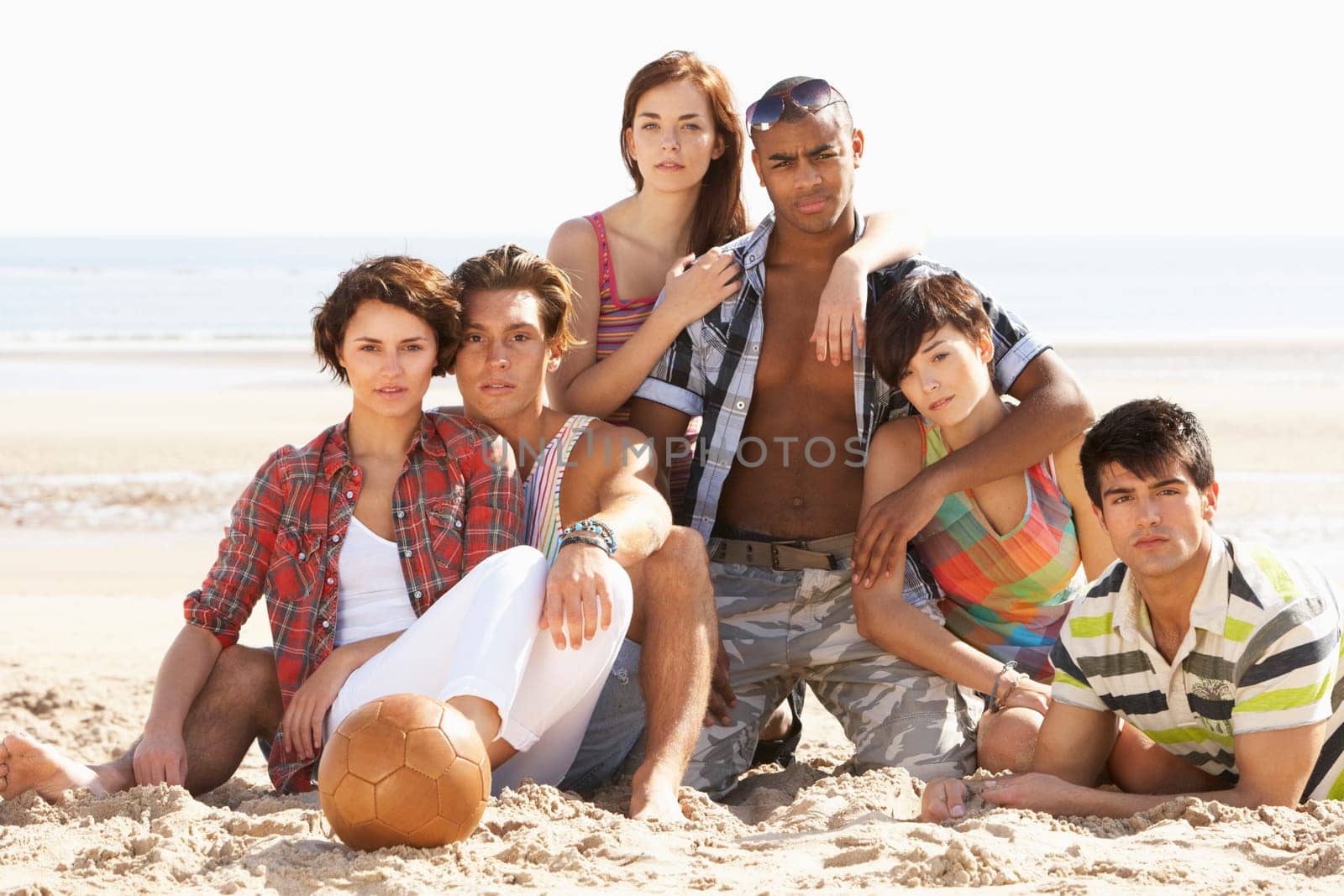 Group Of Friends Relaxing On Beach With Football Together