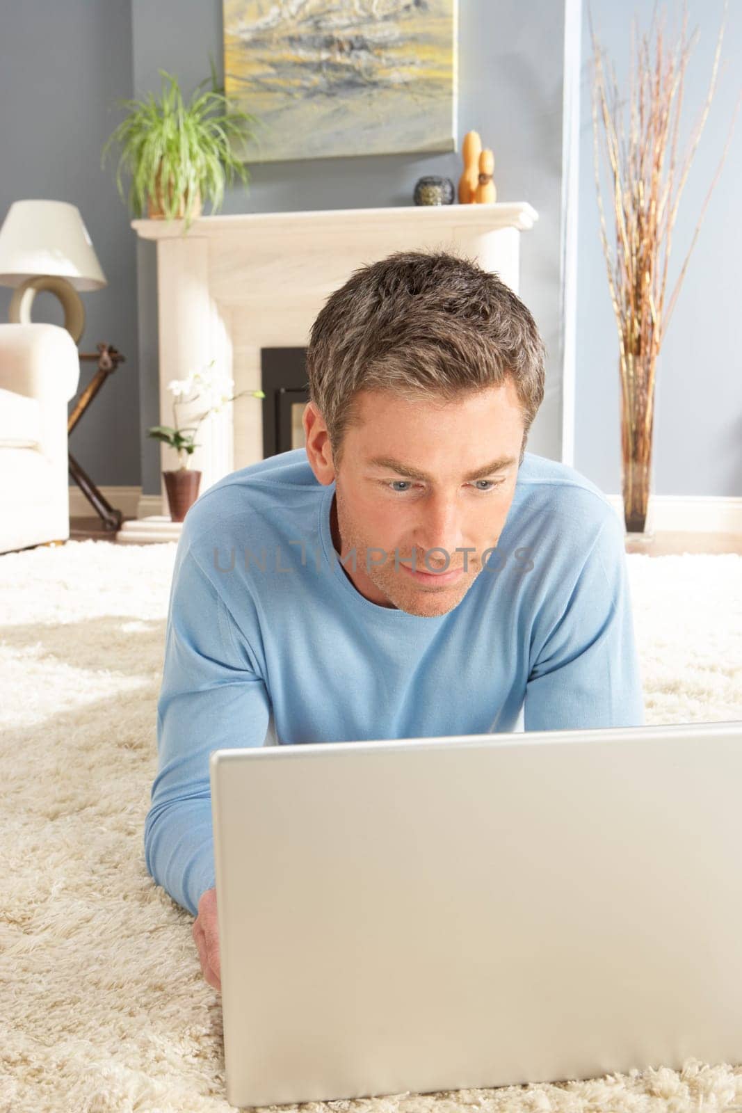 Man Using Laptop Relaxing Laying On Rug At Home