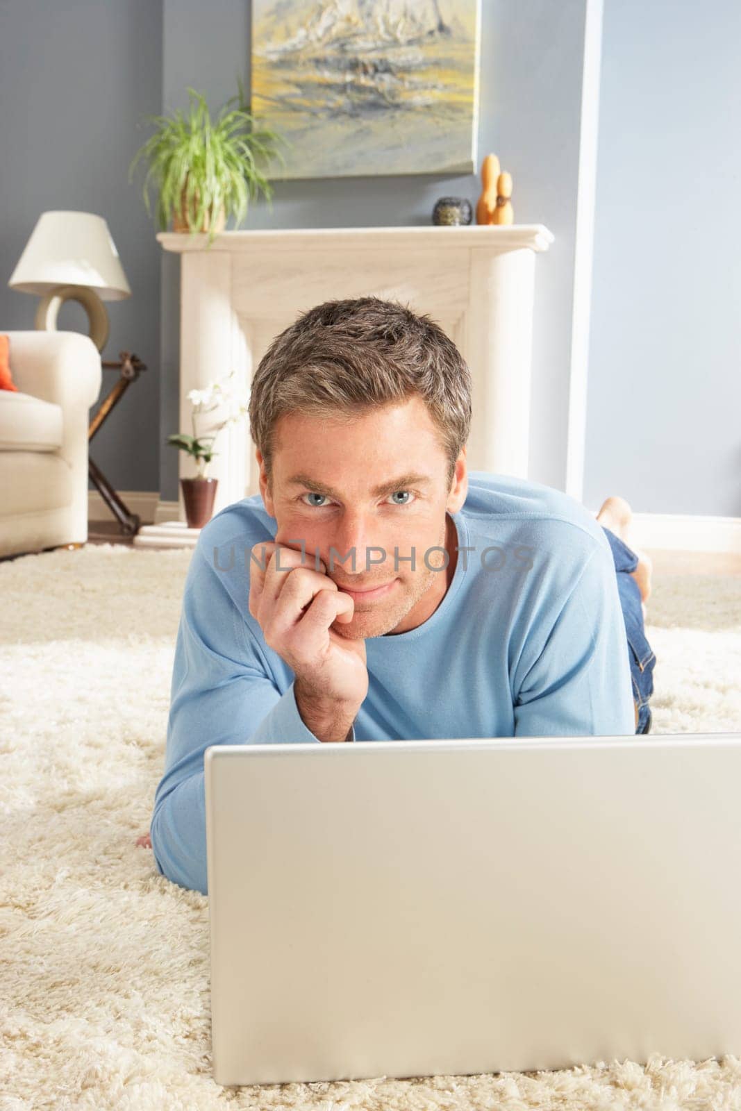 Man Using Laptop Relaxing Laying On Rug At Home