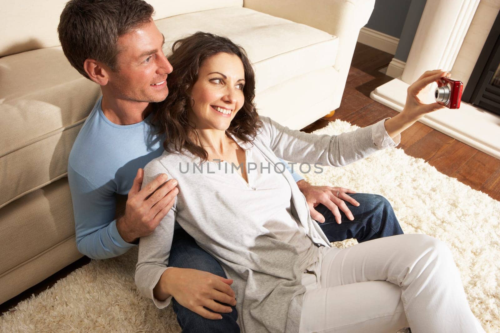Couple Taking Photograph On Digital Camera At Home