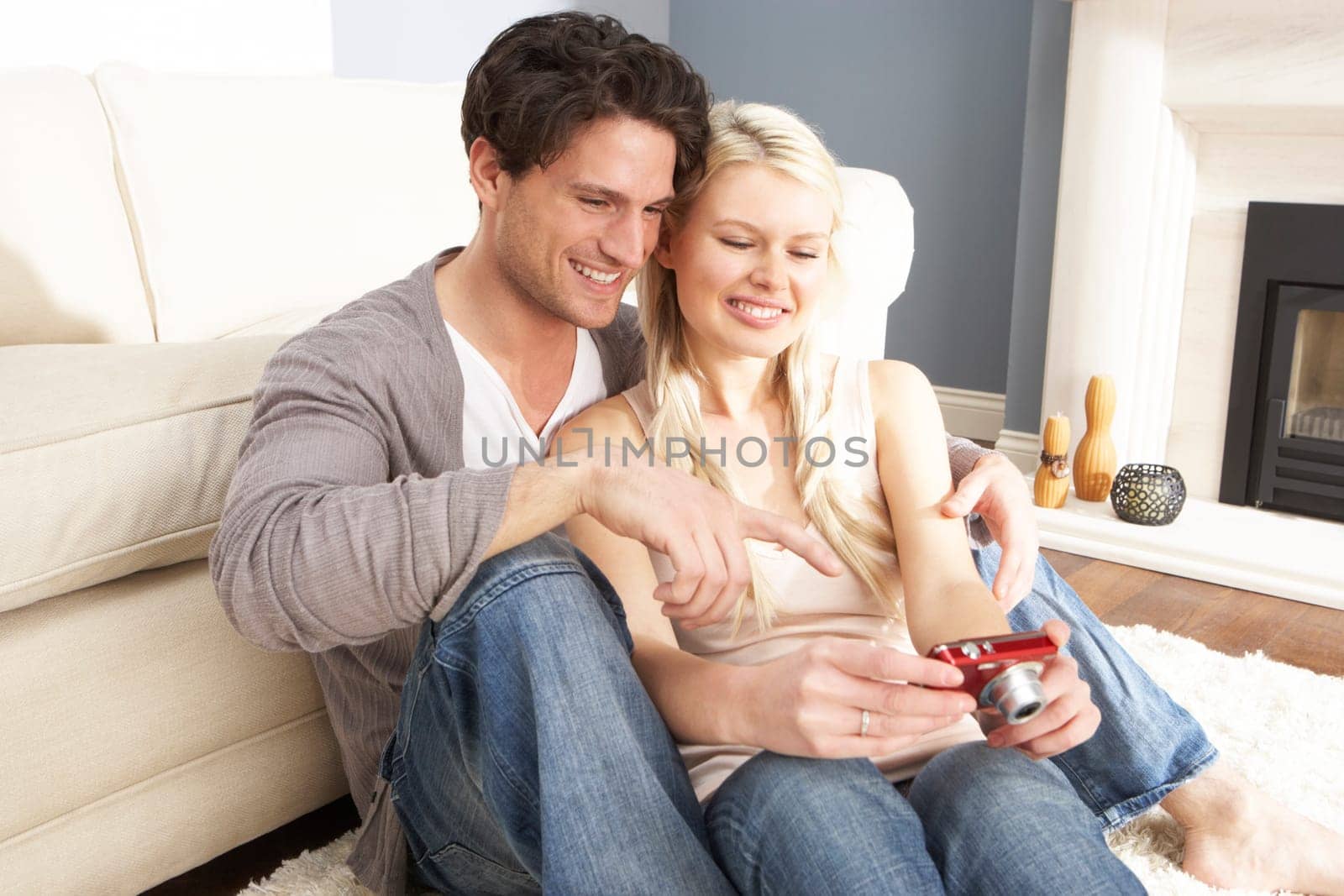 Couple Looking At Pictures On Digital Camera At Home