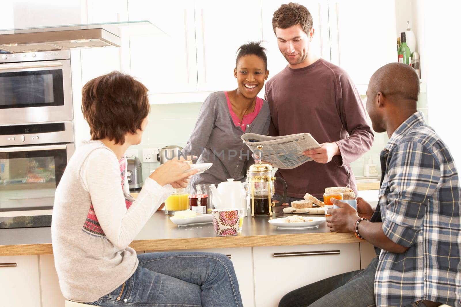 Group Of Young Friends Preparing Breakfast In Modern Kitchen