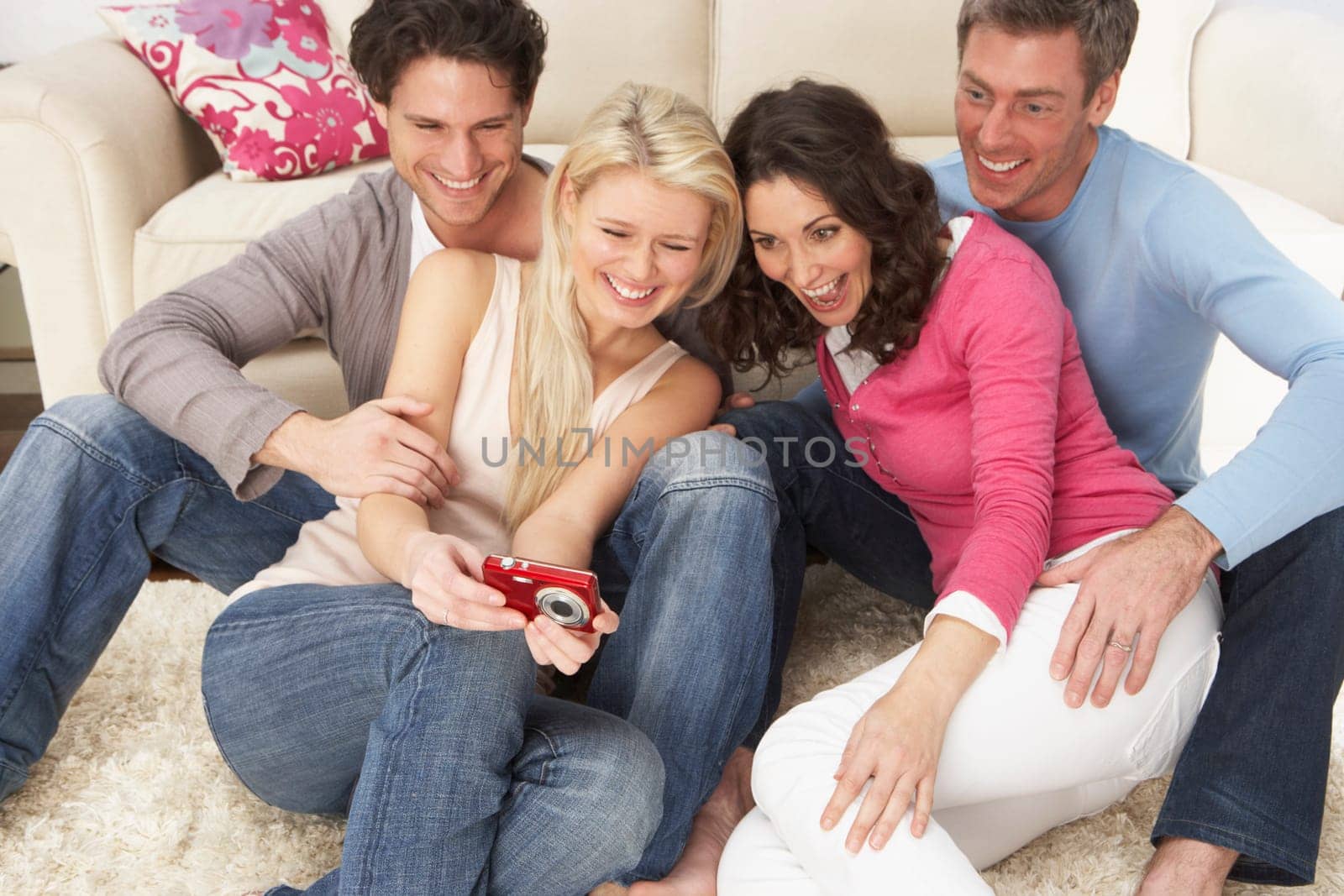 Group Of Friends Looking At Pictures On Digital Camera At Home