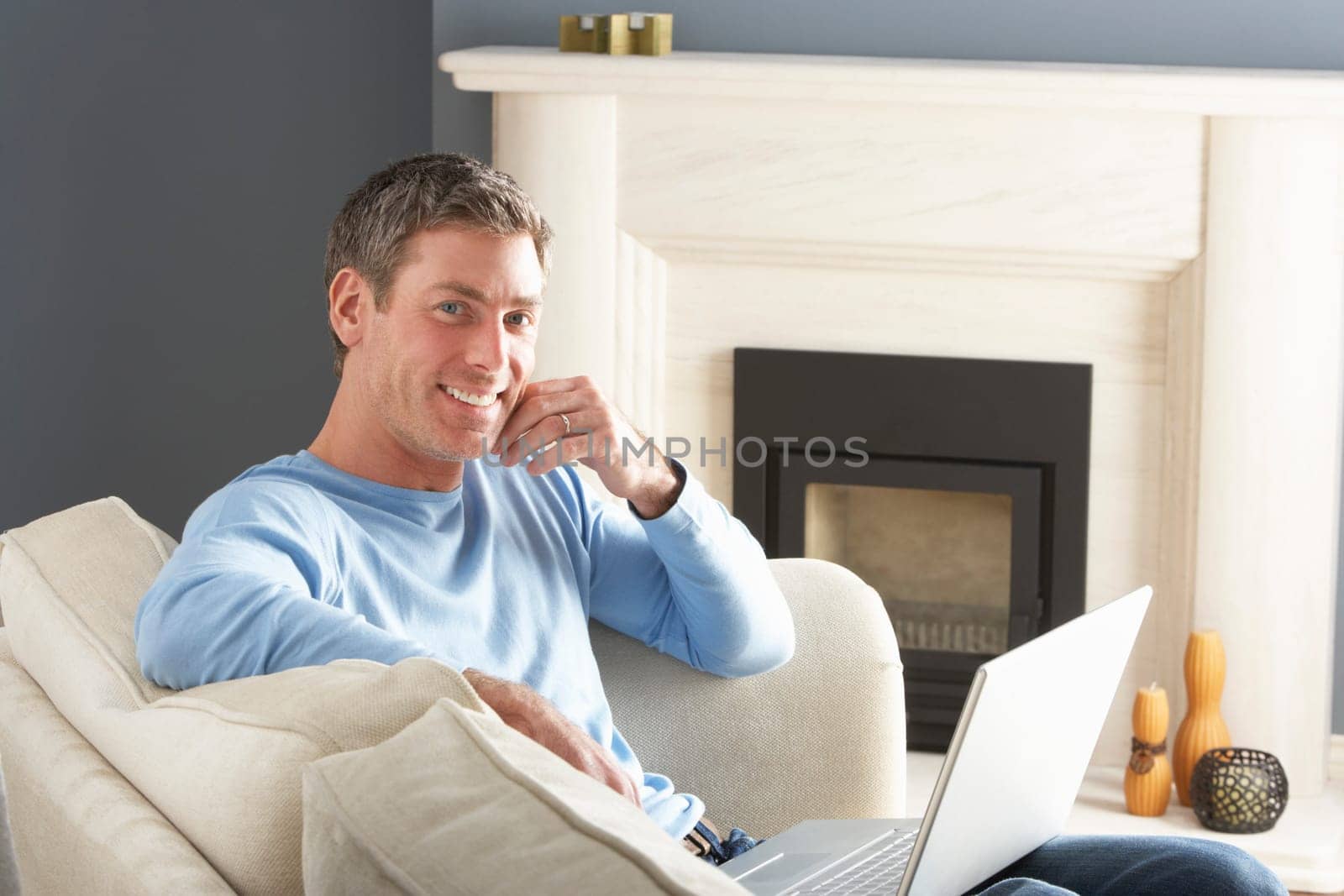 Man Using Laptop Relaxing Sitting On Sofa At Home