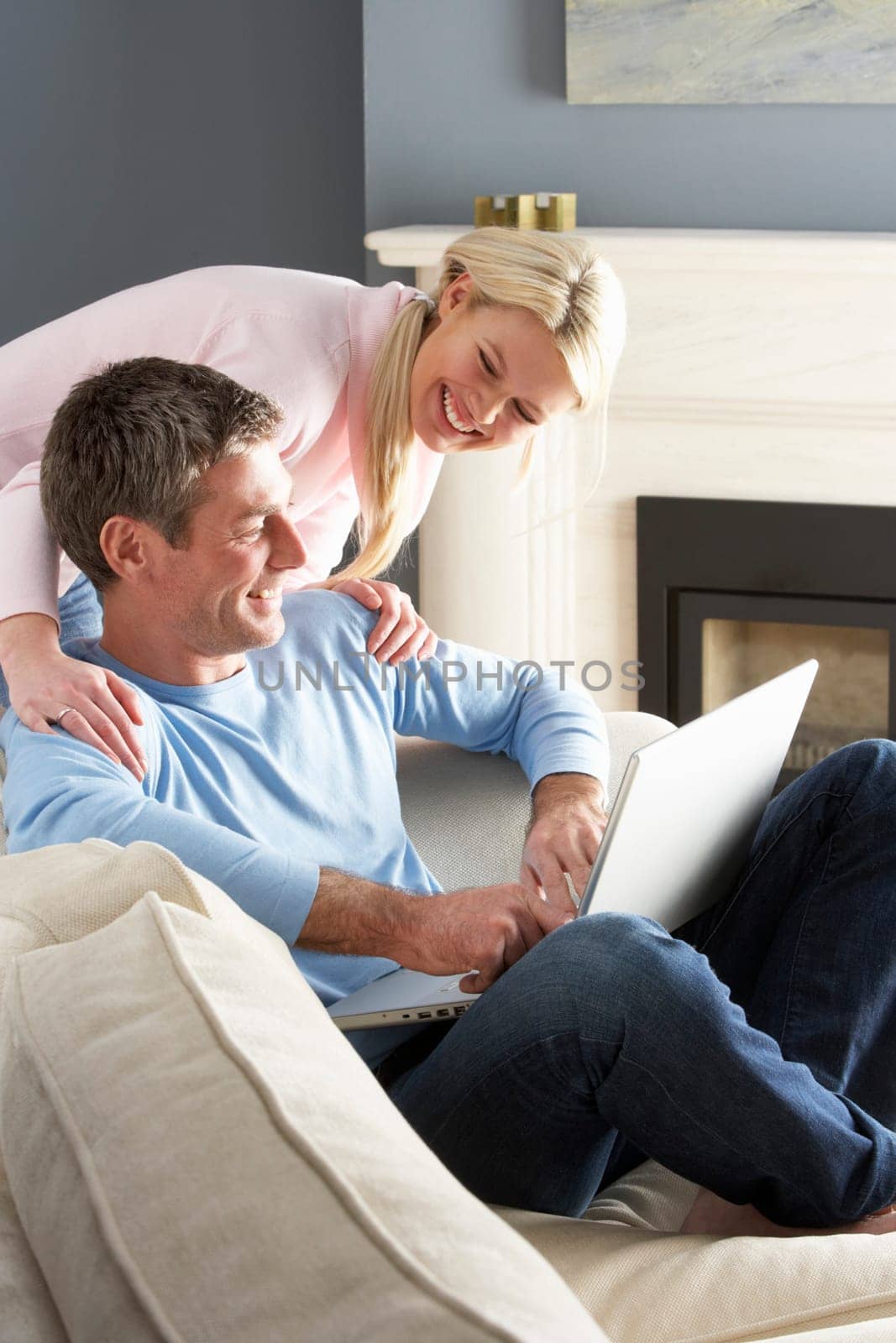 Couple Using Laptop Relaxing Sitting On Sofa At Home