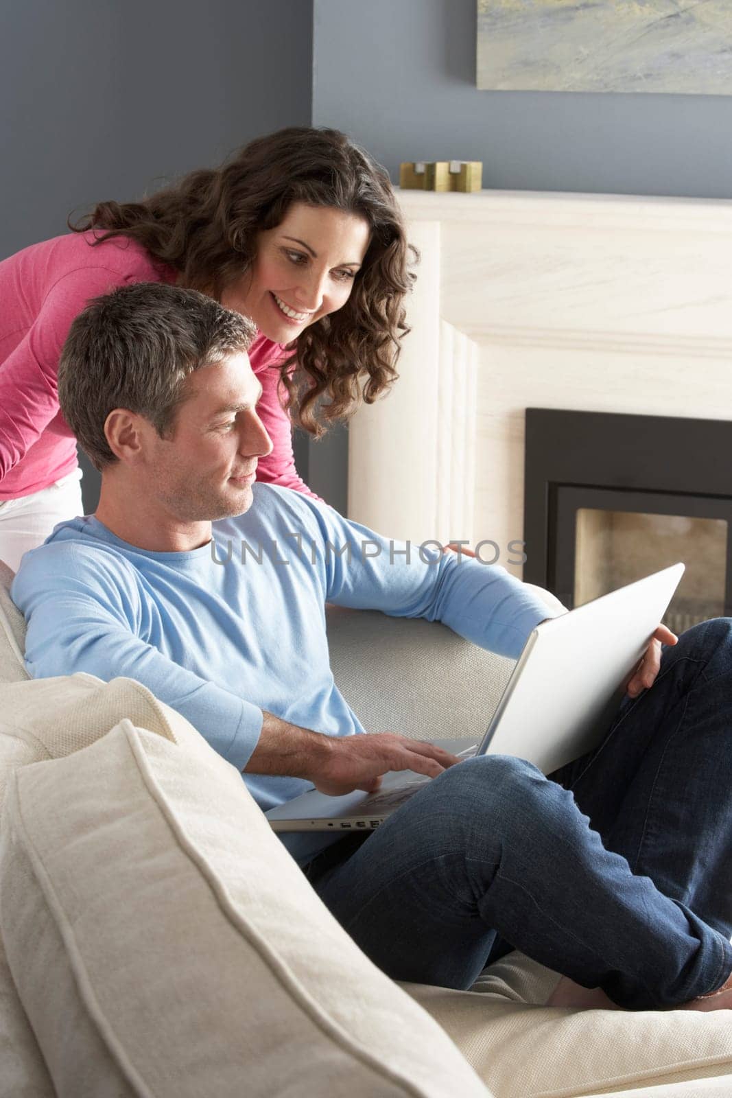 Couple Using Laptop Relaxing Sitting On Sofa At Home