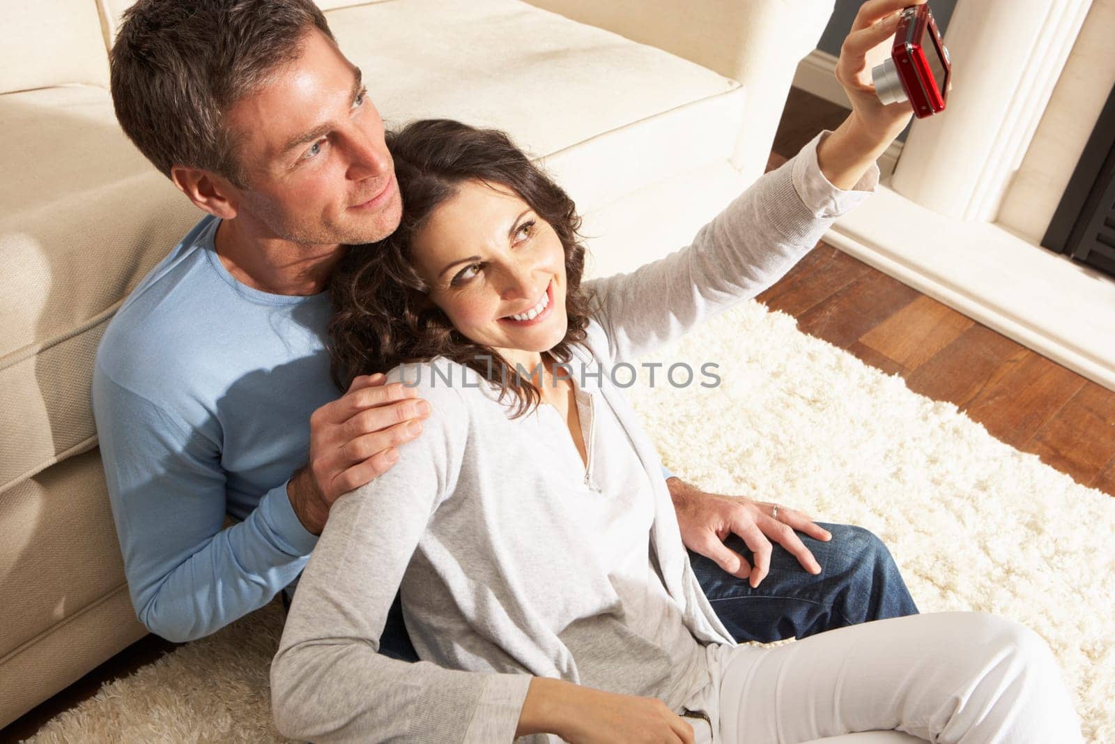 Couple Taking Photograph On Digital Camera At Home