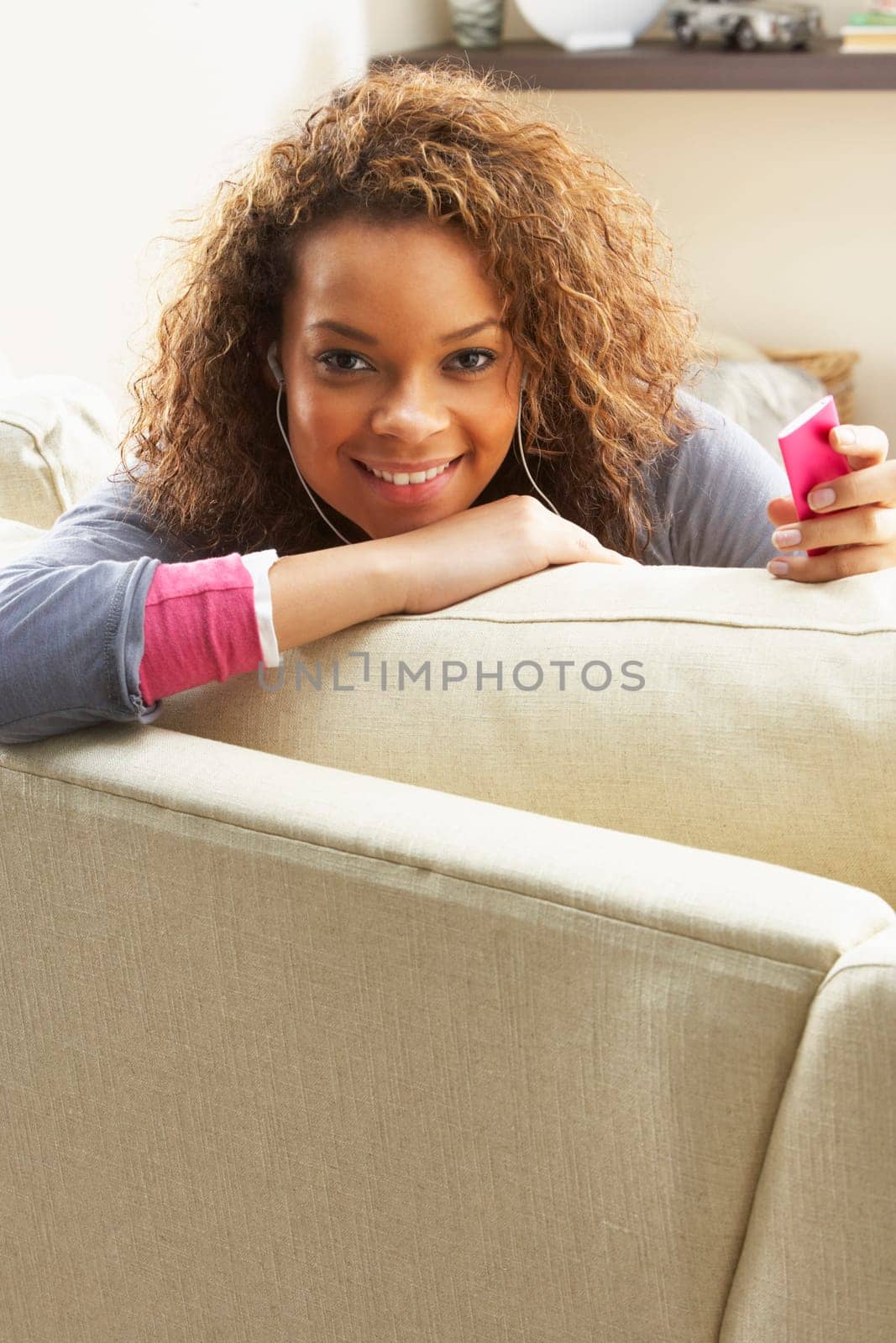 Woman Listening To MP3 Player On Headphones Relaxing Sitting On Rug At Home