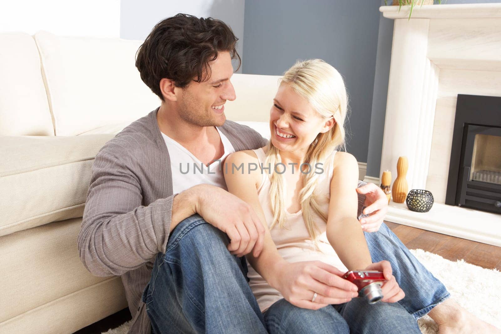 Couple Looking At Pictures On Digital Camera At Home