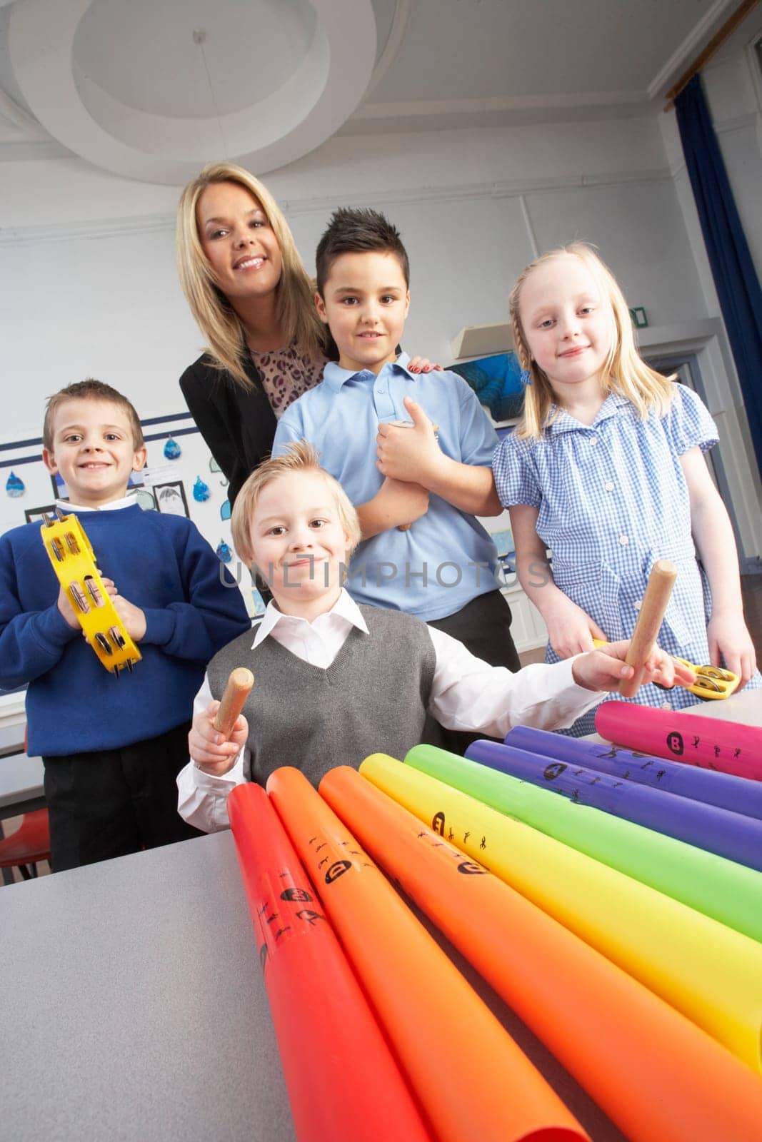 Group Of Primary Schoolchildren And Teacher Having Music Lesson In Classroom