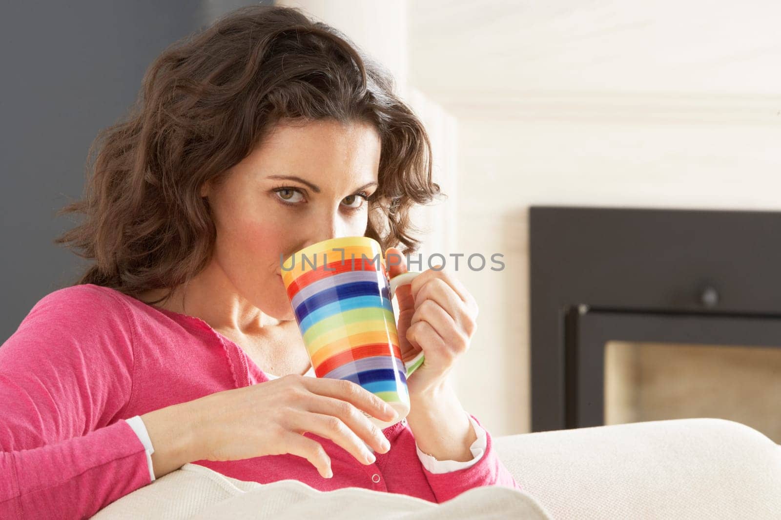 Woman Relaxing On Sofa At Home Drinking Cup Of Coffee