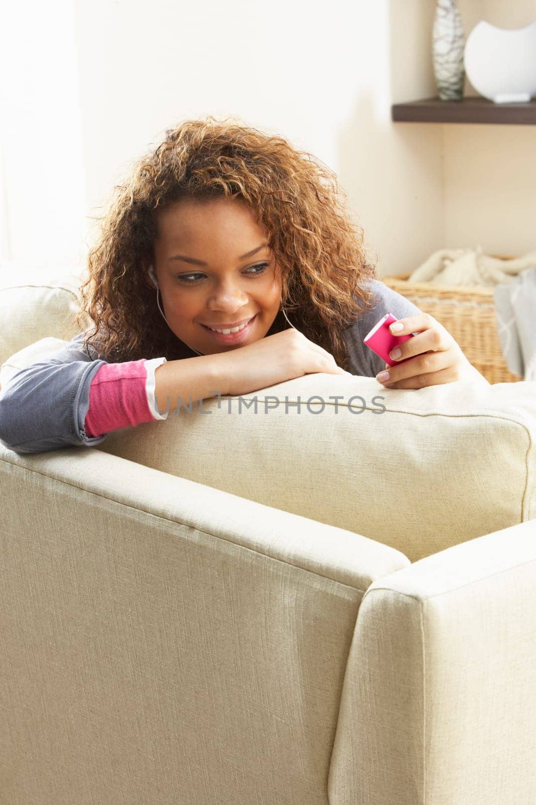 Woman Listening To MP3 Player On Headphones Relaxing Sitting On Rug At Home