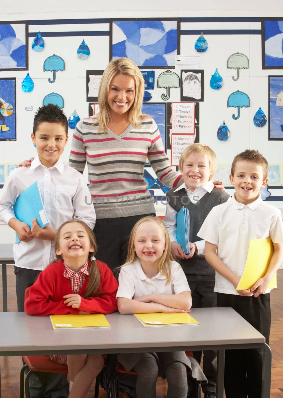 Portrait Of Group Of Primary Schoolchildren And Teacher Sitting At Desk In Classroom