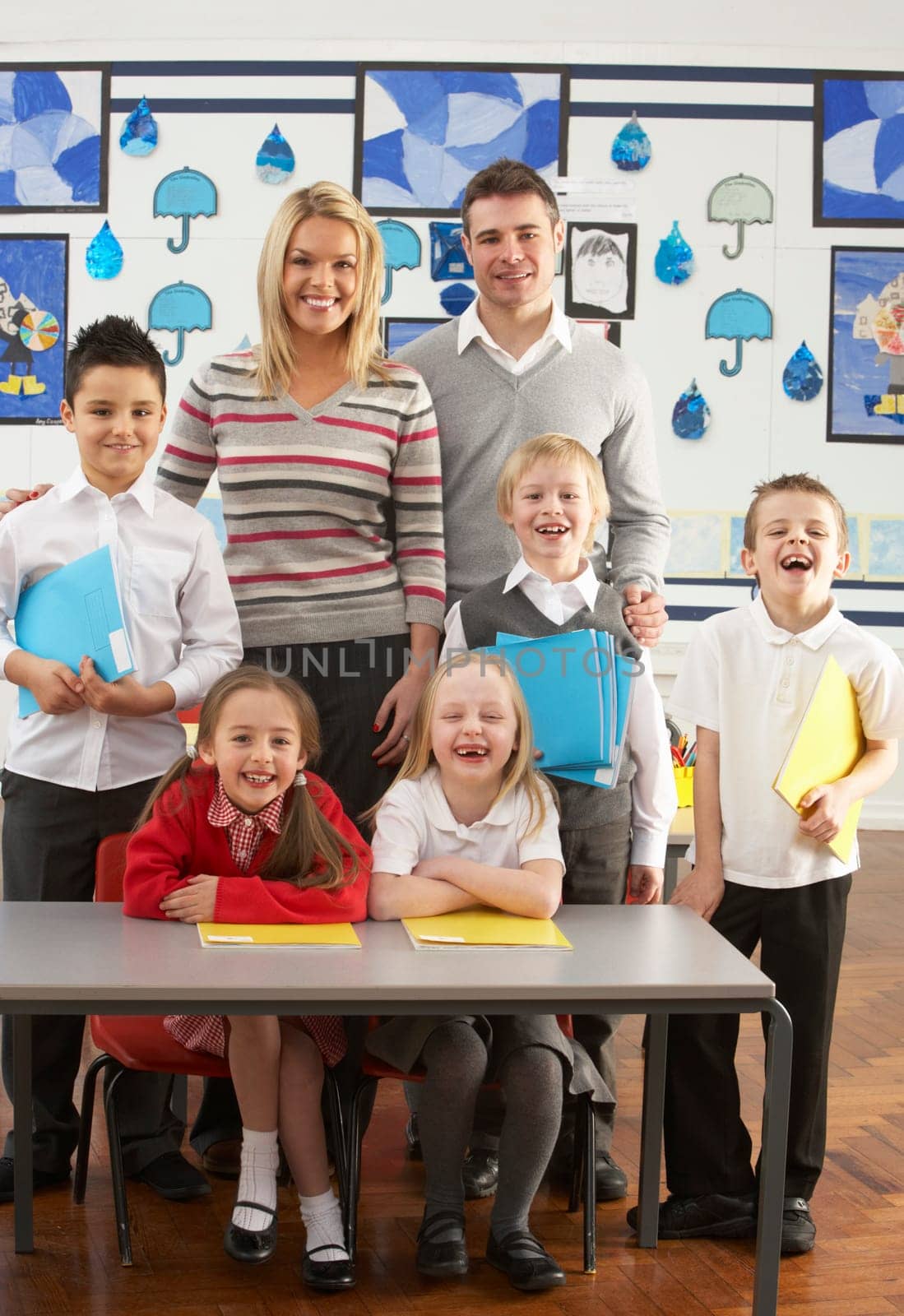 Portrait Of Group Of Primary Schoolchildren And Teachers Sitting At Desk In Classroom