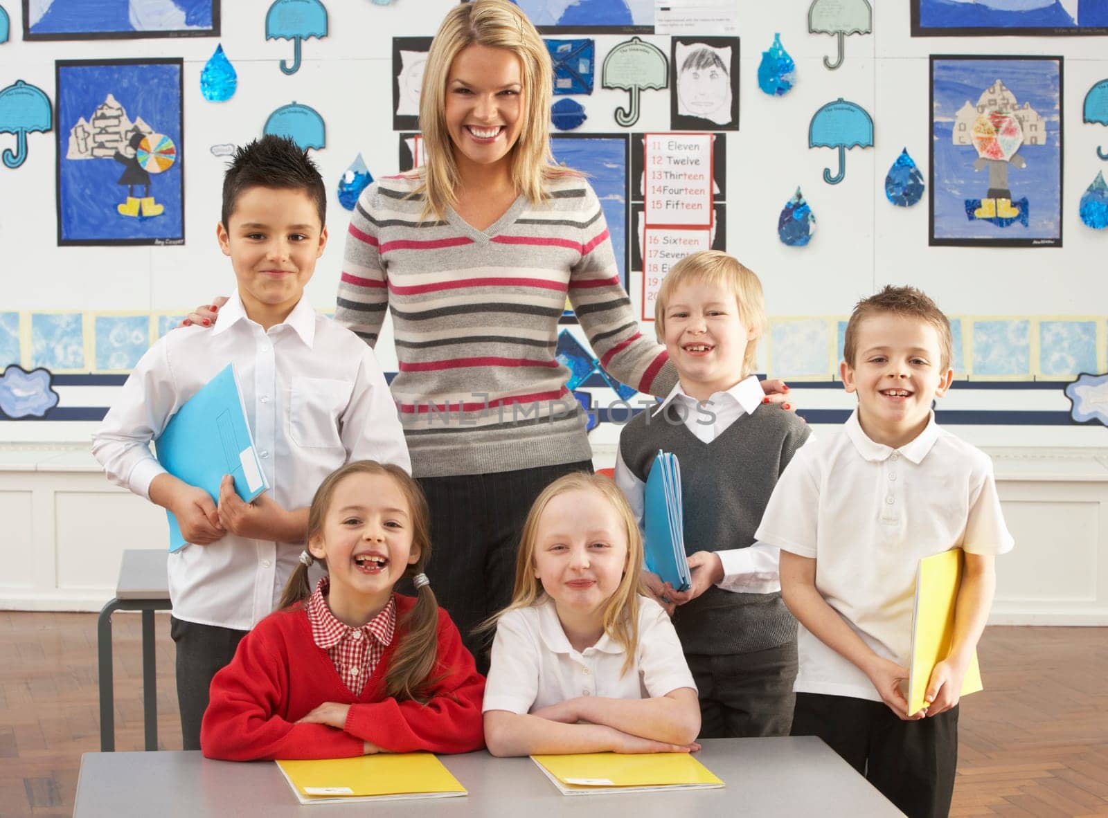 Portrait Of Group Of Primary Schoolchildren And Teacher Sitting At Desk In Classroom