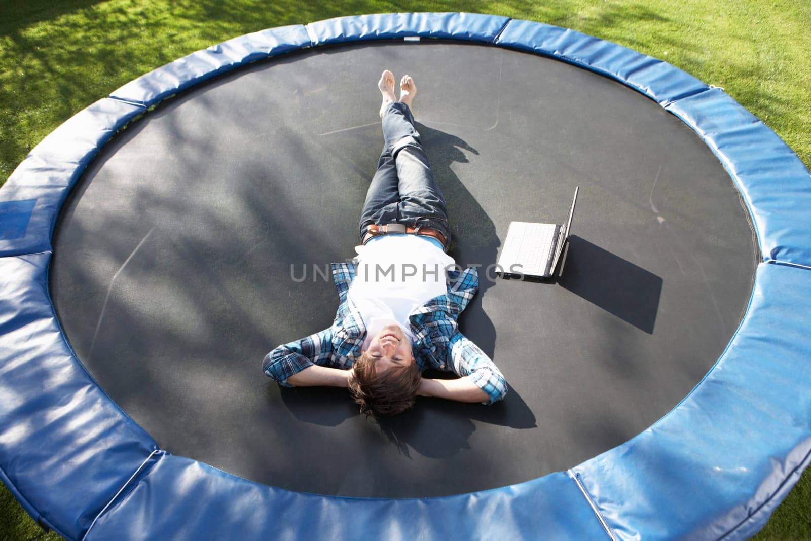 Young Man Relaxing On Trampoline With Laptop