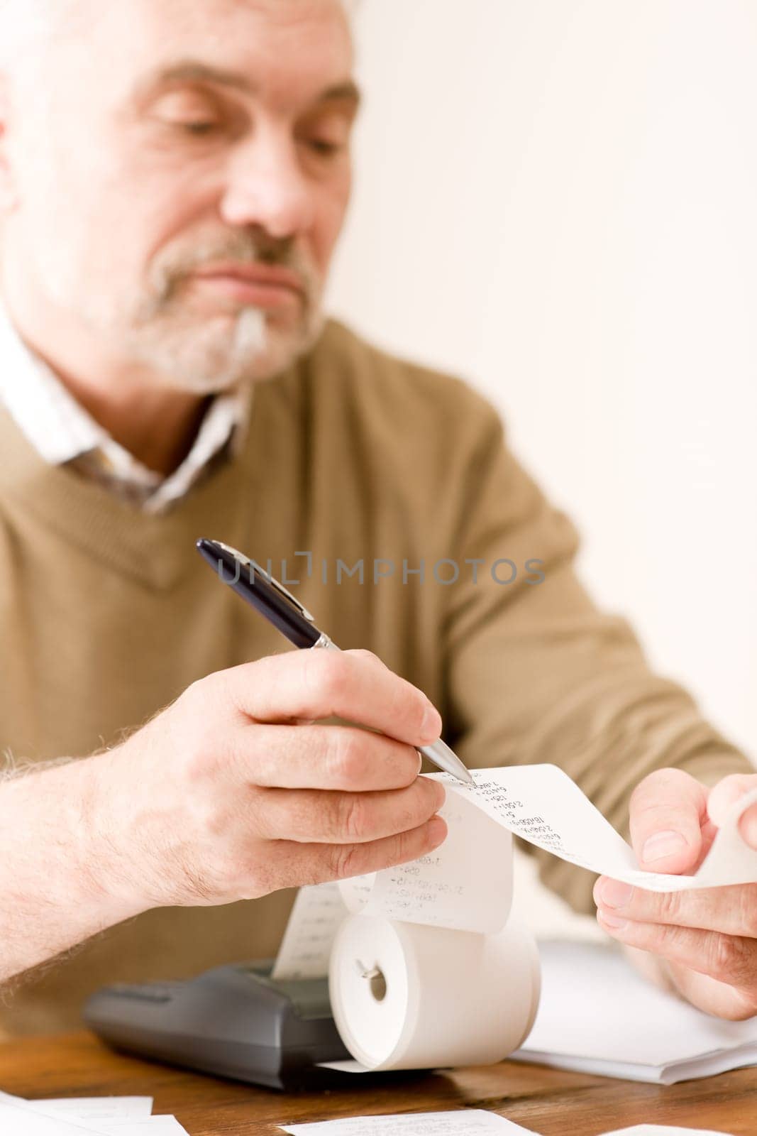 Senior mature man - home office, paper tape calculator