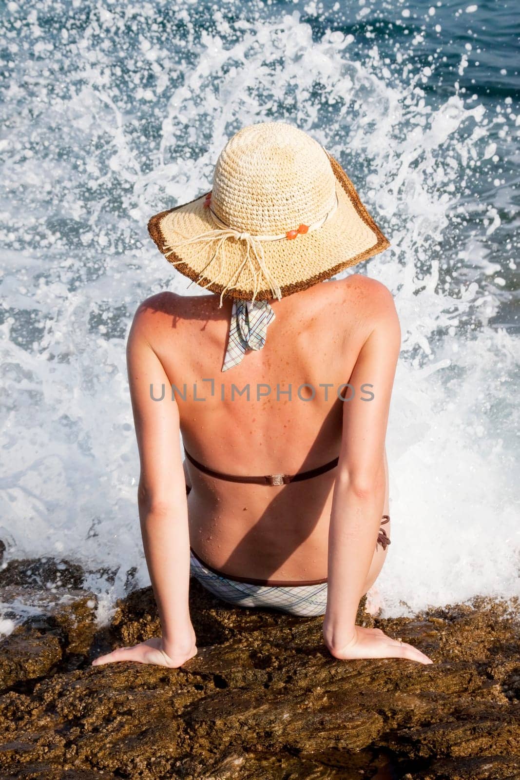 woman with hat sitting on rocks