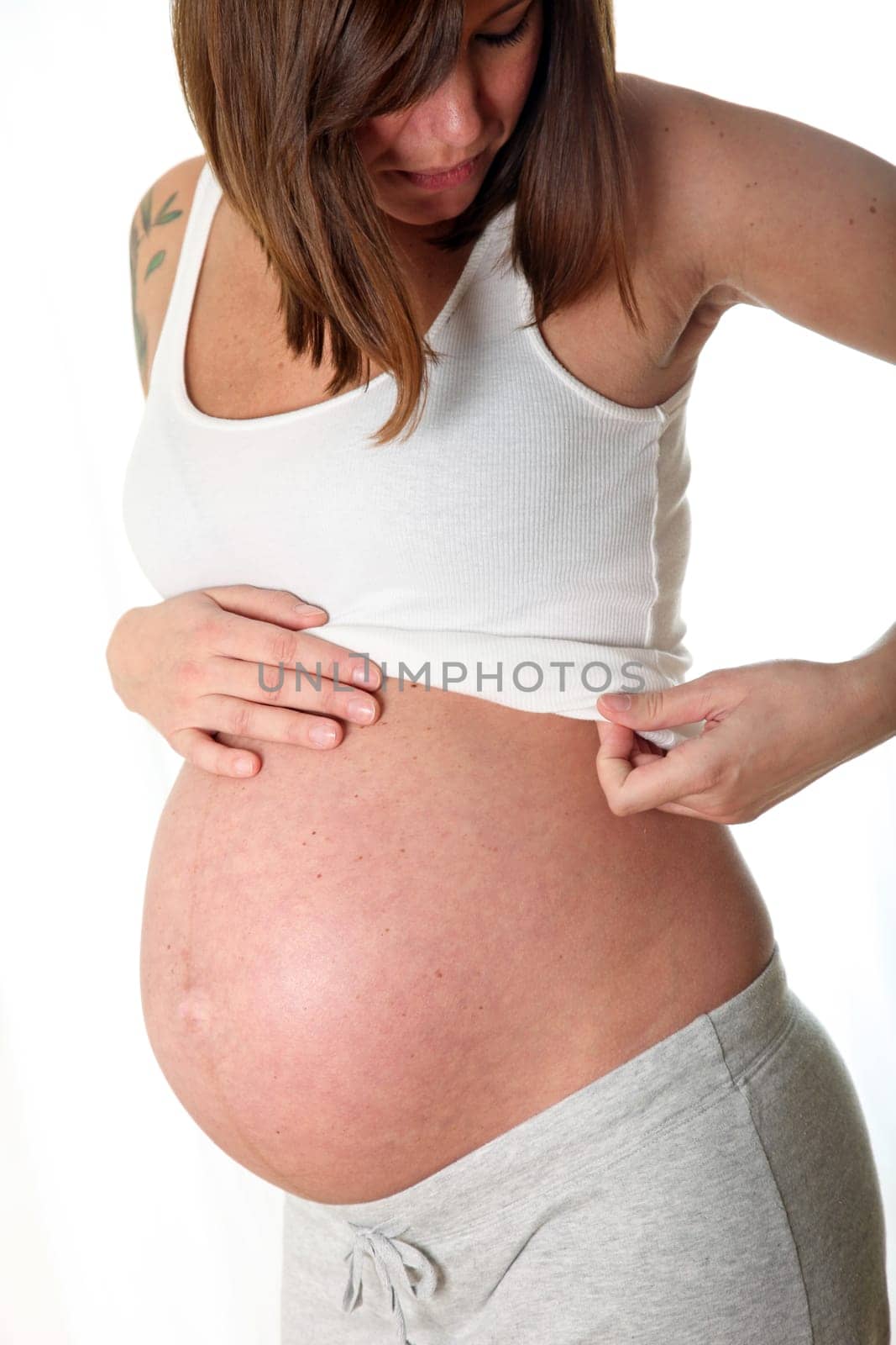 Highly pregnant woman in casual look holding her belly