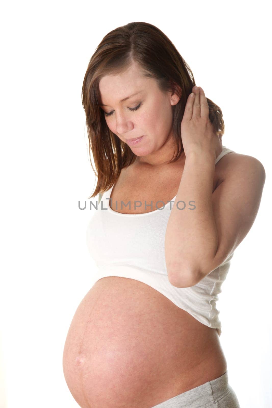 Pregnant,young woman in front of white background looking happily at her belly