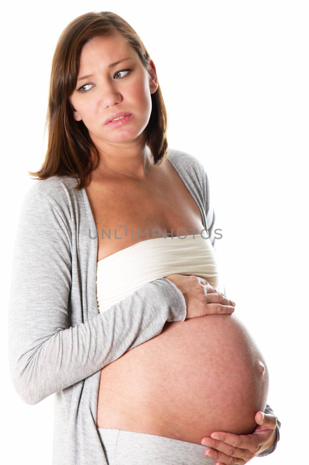 pregnant woman suffers and has complaints: she looks unhappily to the side and holds her belly