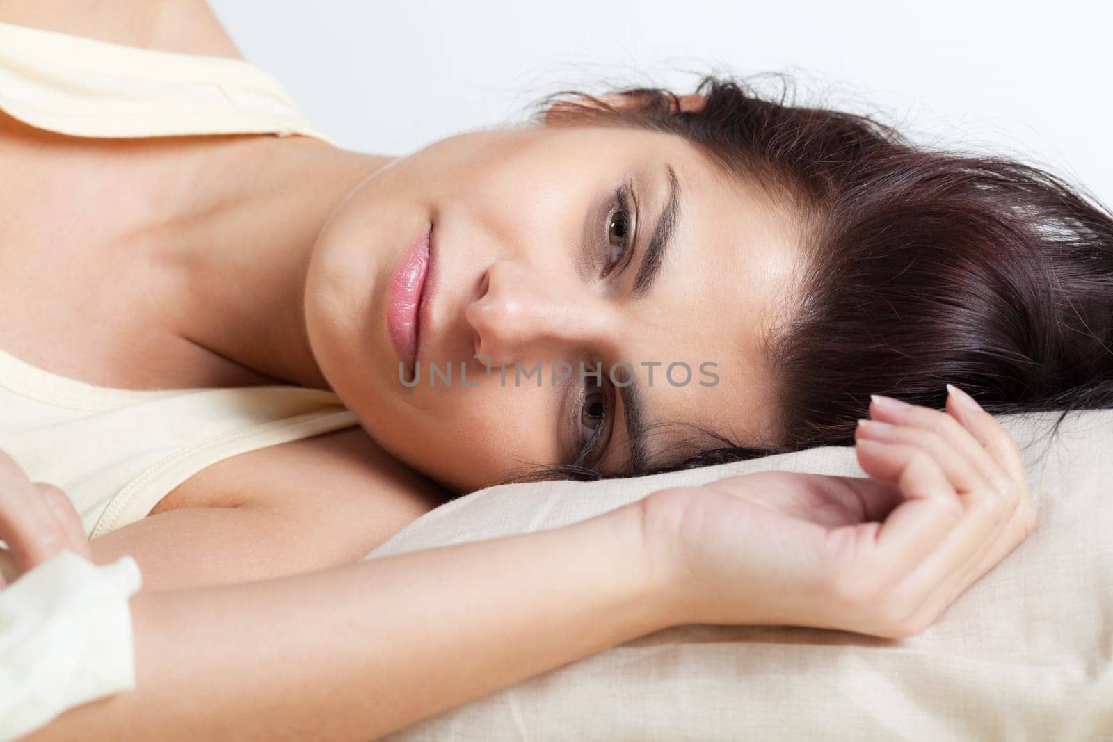 Pretty young brunette woman lying in bed