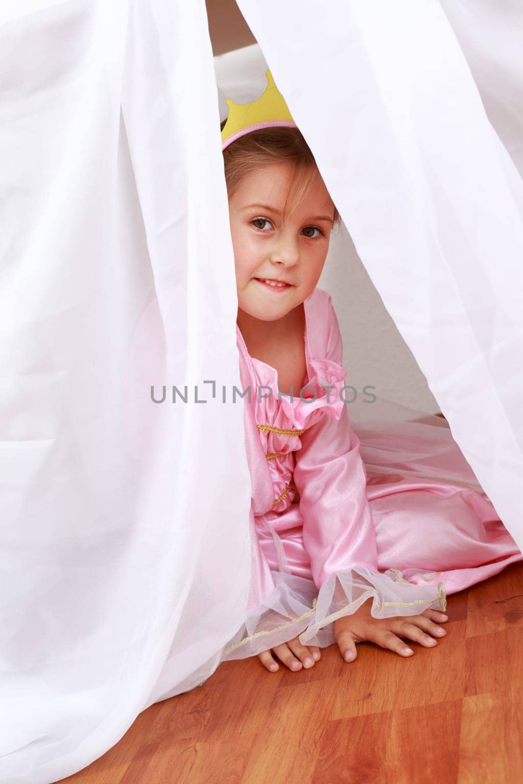 Adorable girl dressed as princess playing hide-and-seek at home
