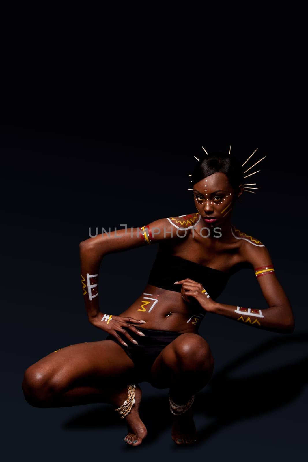 Beautiful exotic African female fashion with tribal yellow red and white makeup cosmetics and sticks in hai, in dance position.
