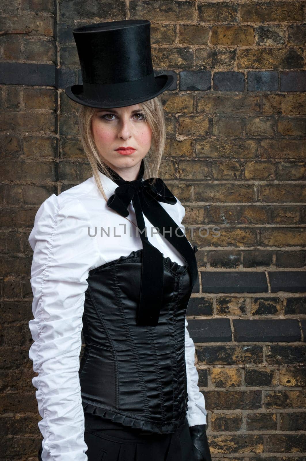 Portrait of beautiful woman in late victorian costume against brick wall