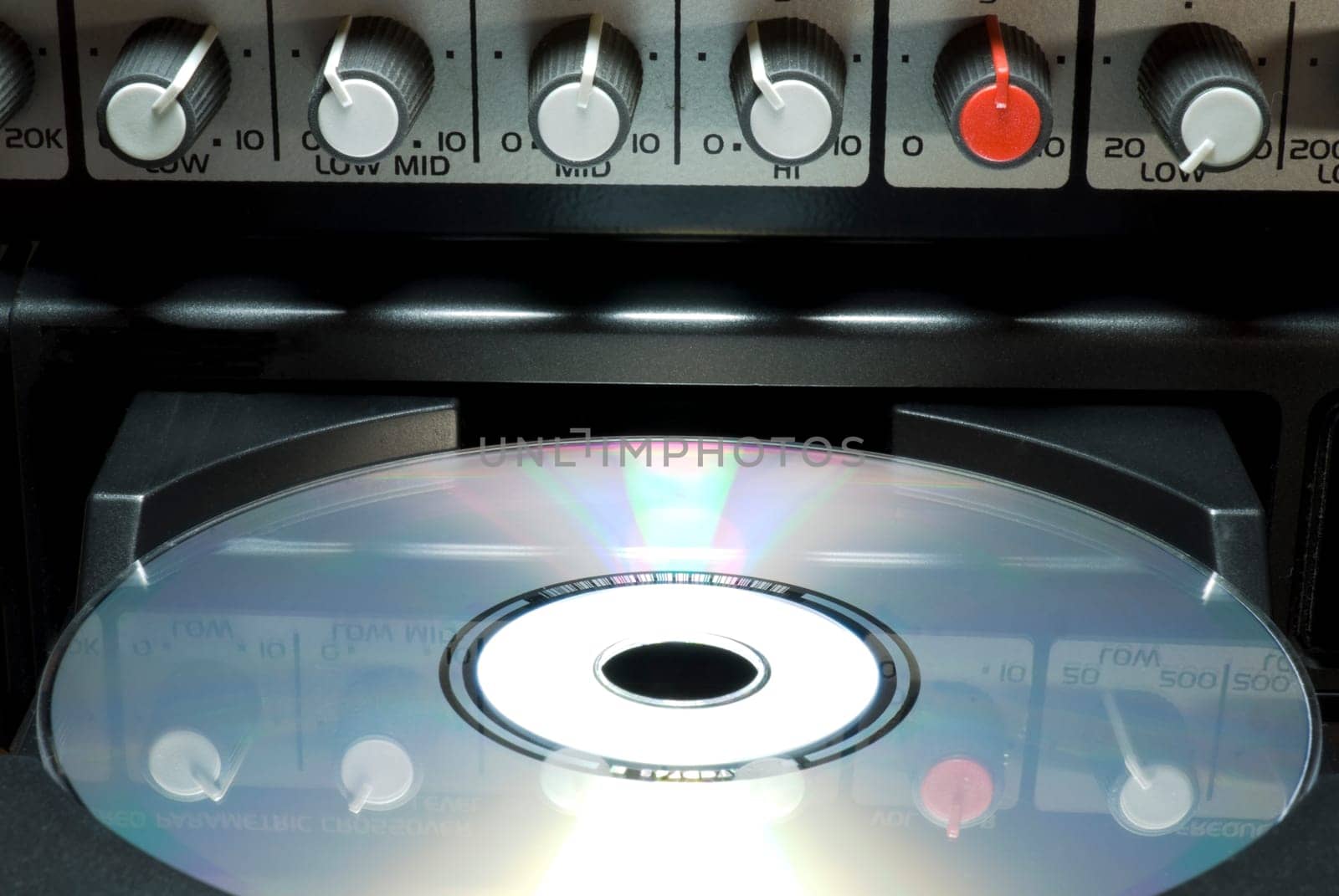 Detail shot of a CD in a player&#039 s drawer with crossover buttons on top. Front shot with dark background.