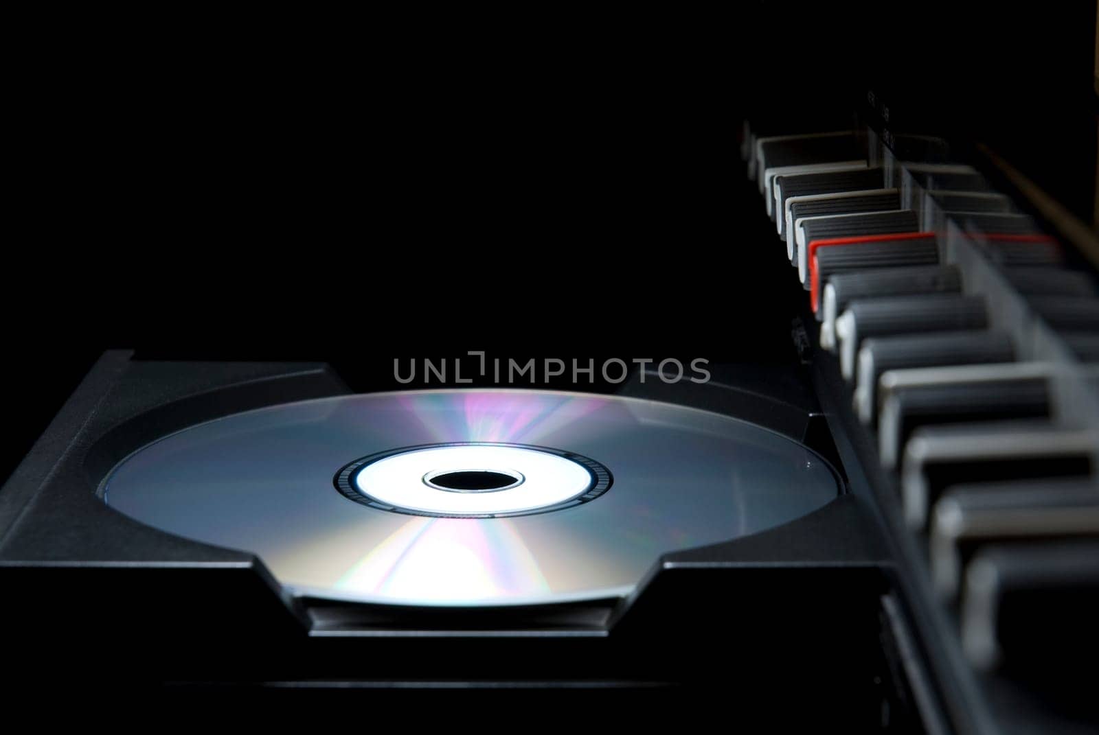 Detail shot of a CD in a player&#039 s drawer with crossover buttons on the top right, in perspective. Side shot with dark background.