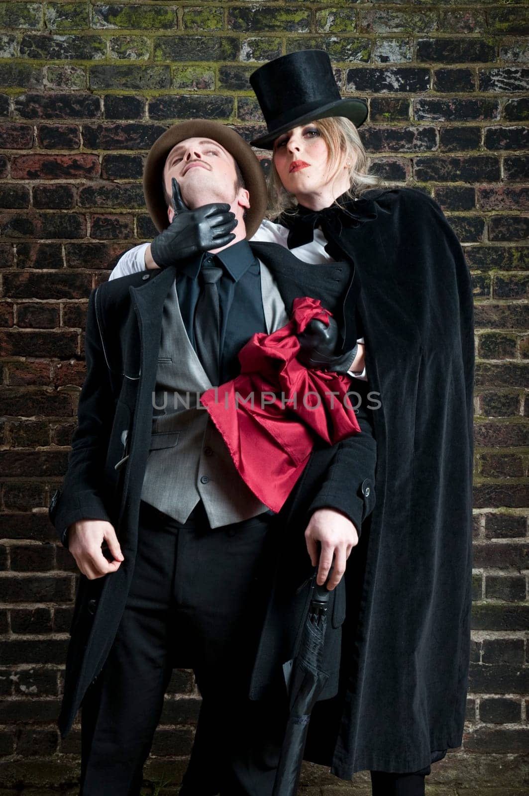 Fashion shot of woman  dressed as Jack the Ripper stealing man&#039 s handkerchief.