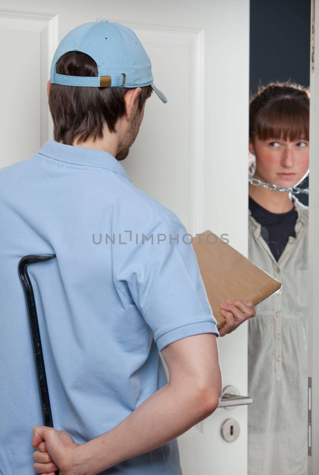 fake delivery man holding a small package and crowbar while woman opening the door