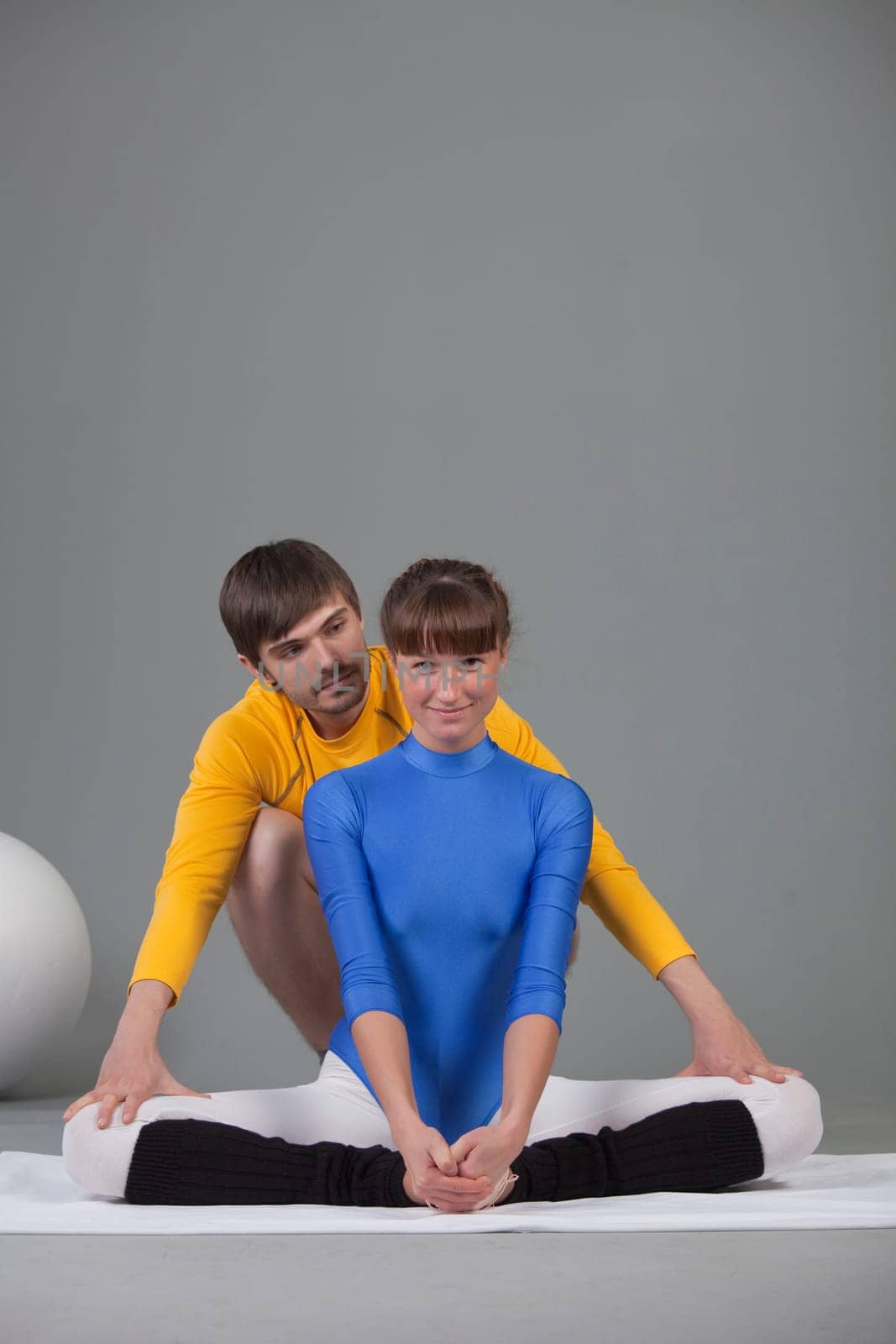 personal trainer helping woman by stretching exercises