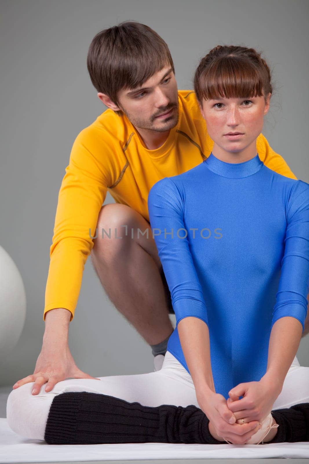 personal trainer helping woman by stretching exercises