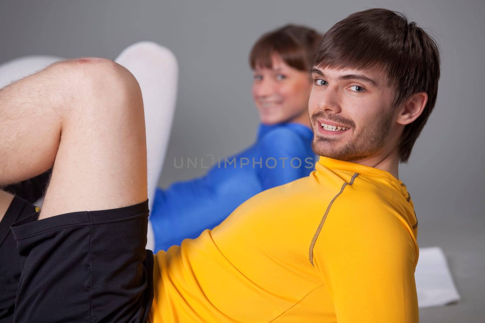 personal trainer and woman in blue leotard doing abdominal exercises together