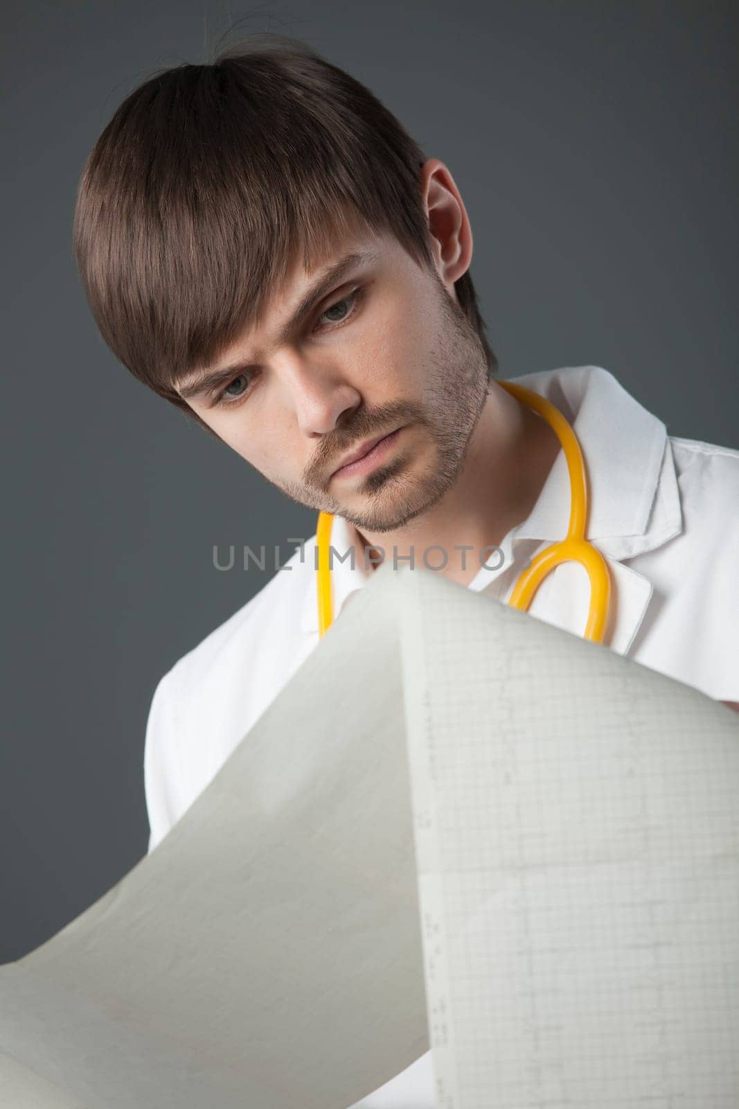 doctor with cardiogram over grey background in studio