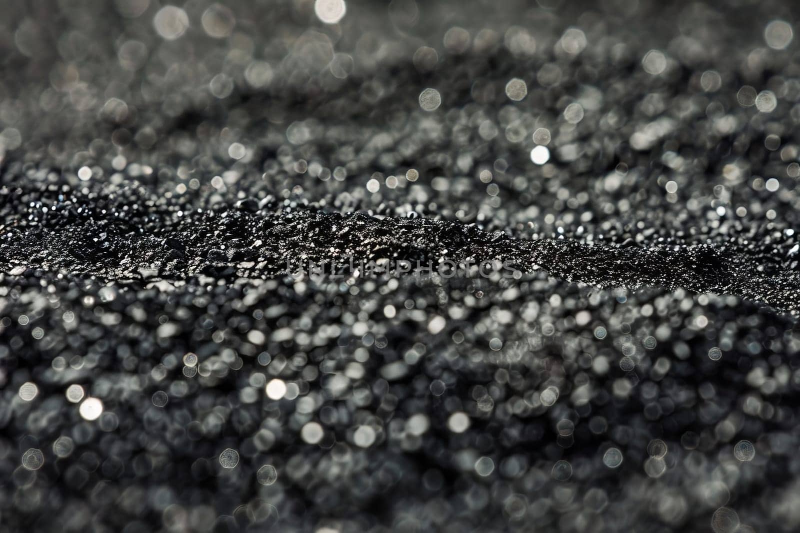 Glittering macro close-up of black sand with bokeh effect.