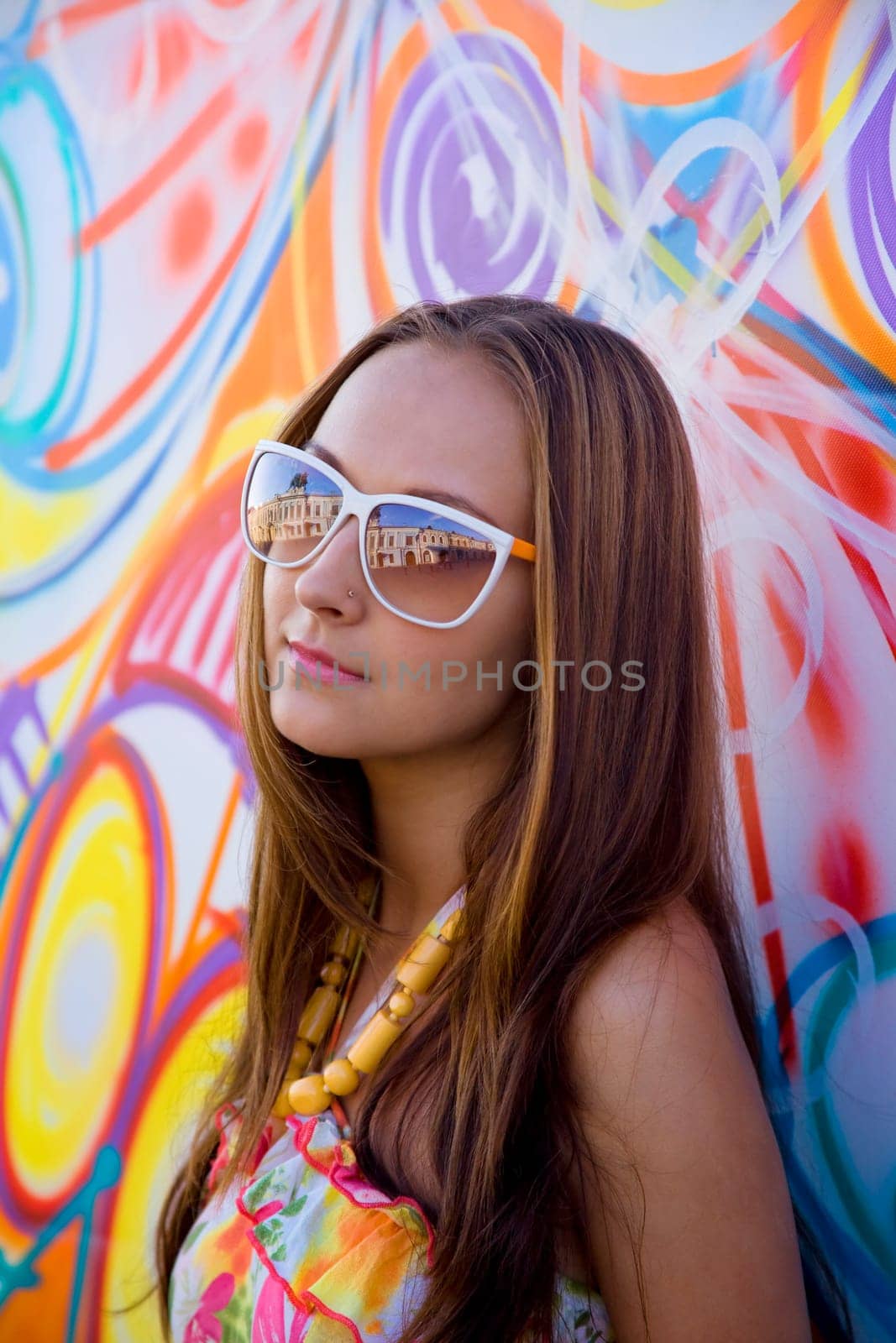 Young woman in glasses stand near graffiti wall