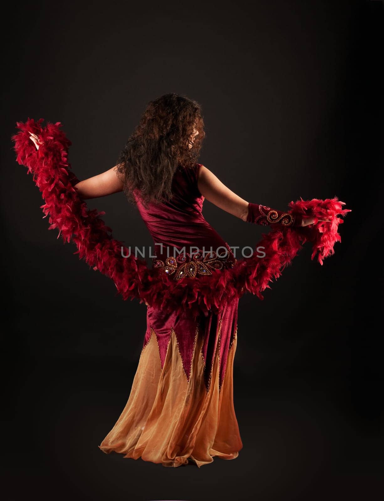 Woman in dark red arabian costume dance with boa
