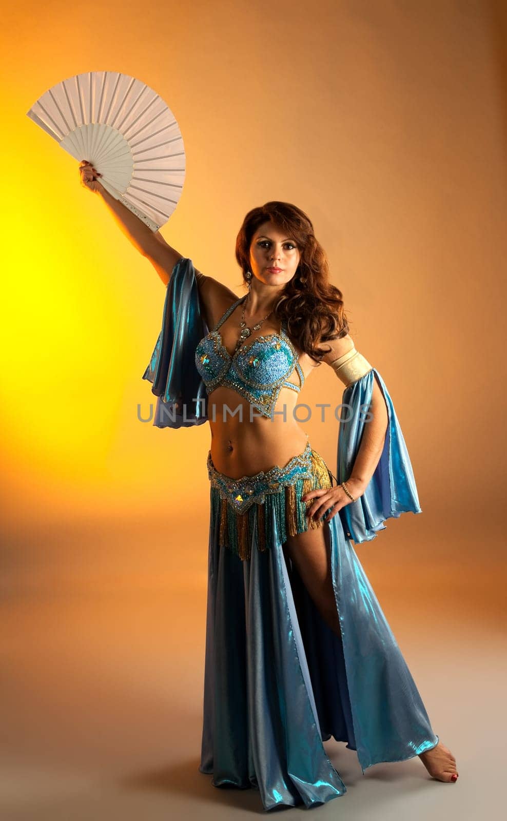 Mature woman in blue arabian costume belly dance with fan