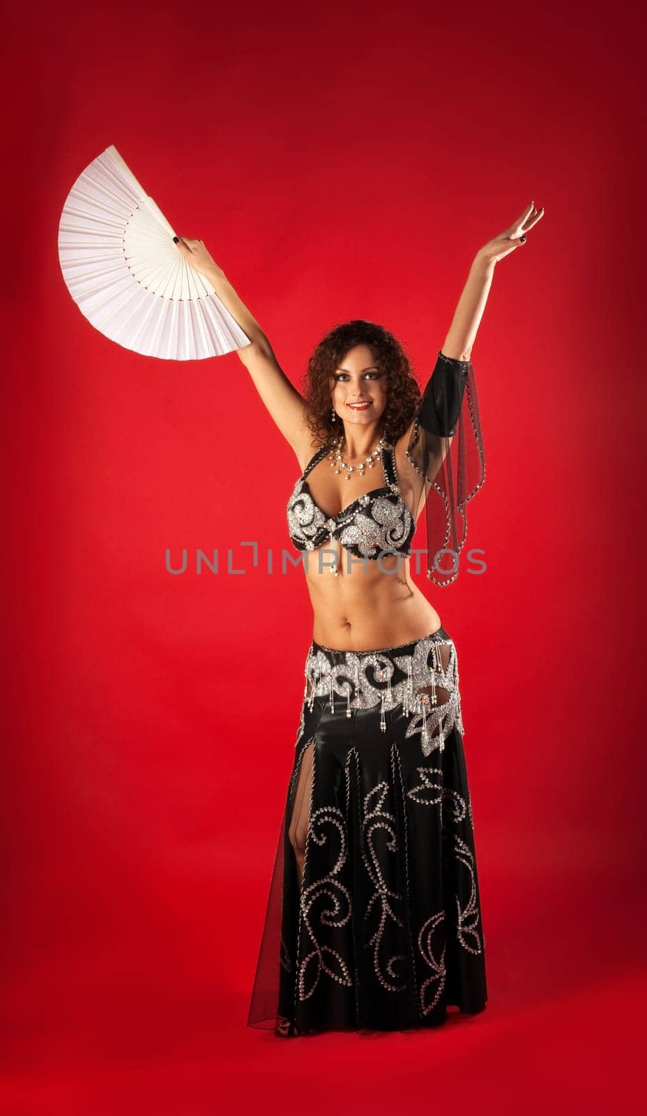 Woman in black arabian costume belly dance with fan