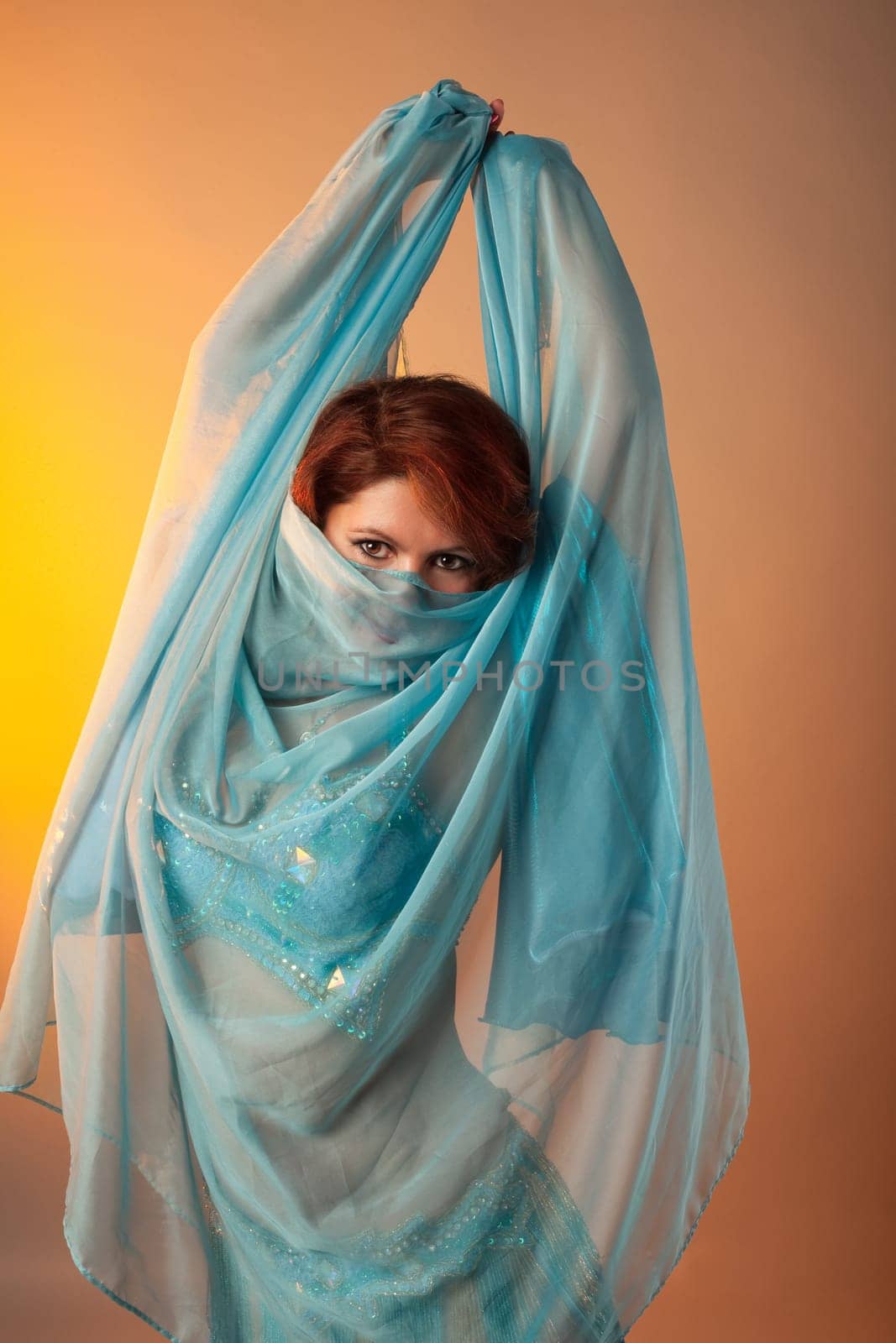 dancing woman in arabian costume hide face with veil