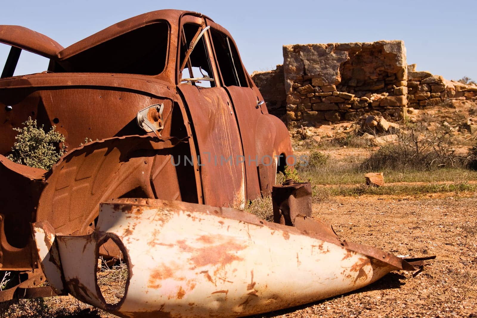 an old rusting car and ruins in the desert