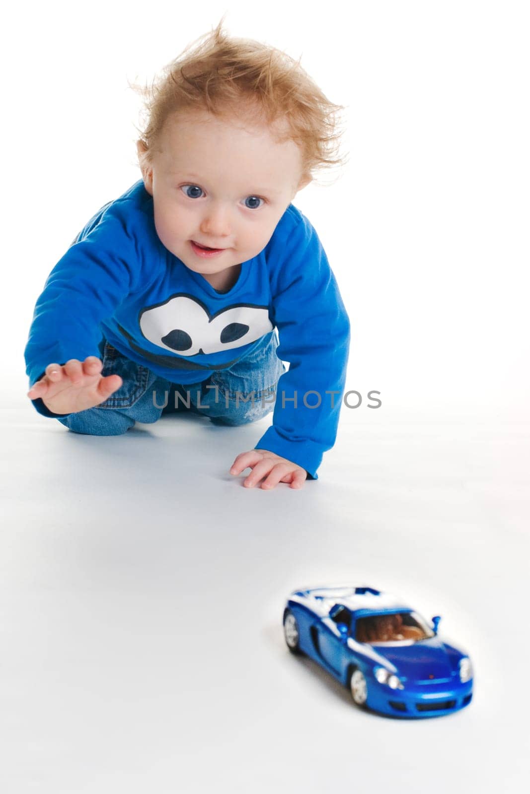 Baby playing with blue car toy on white